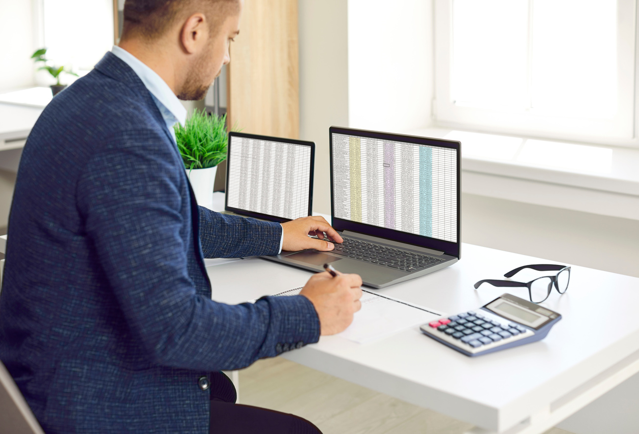 Busy Concentrated Male Financier Working in Office with Excel Spreadsheets and Calculator.